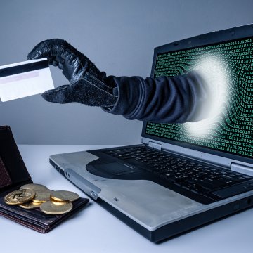 identity guard service identity theft man with black glove coming out of the laptop monitor stealing credit card from wallet on the table